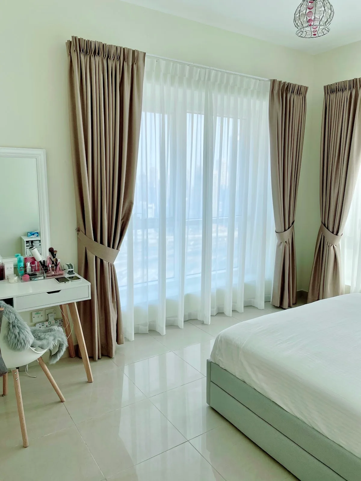Bedroom with floor-length pinch-pleat curtains and white sheers