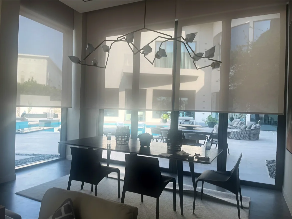 Dining room with sheer roller blinds overlooking a pool