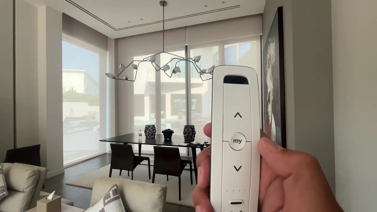 Motorised roller blind being operated by a handheld remote in a dining room