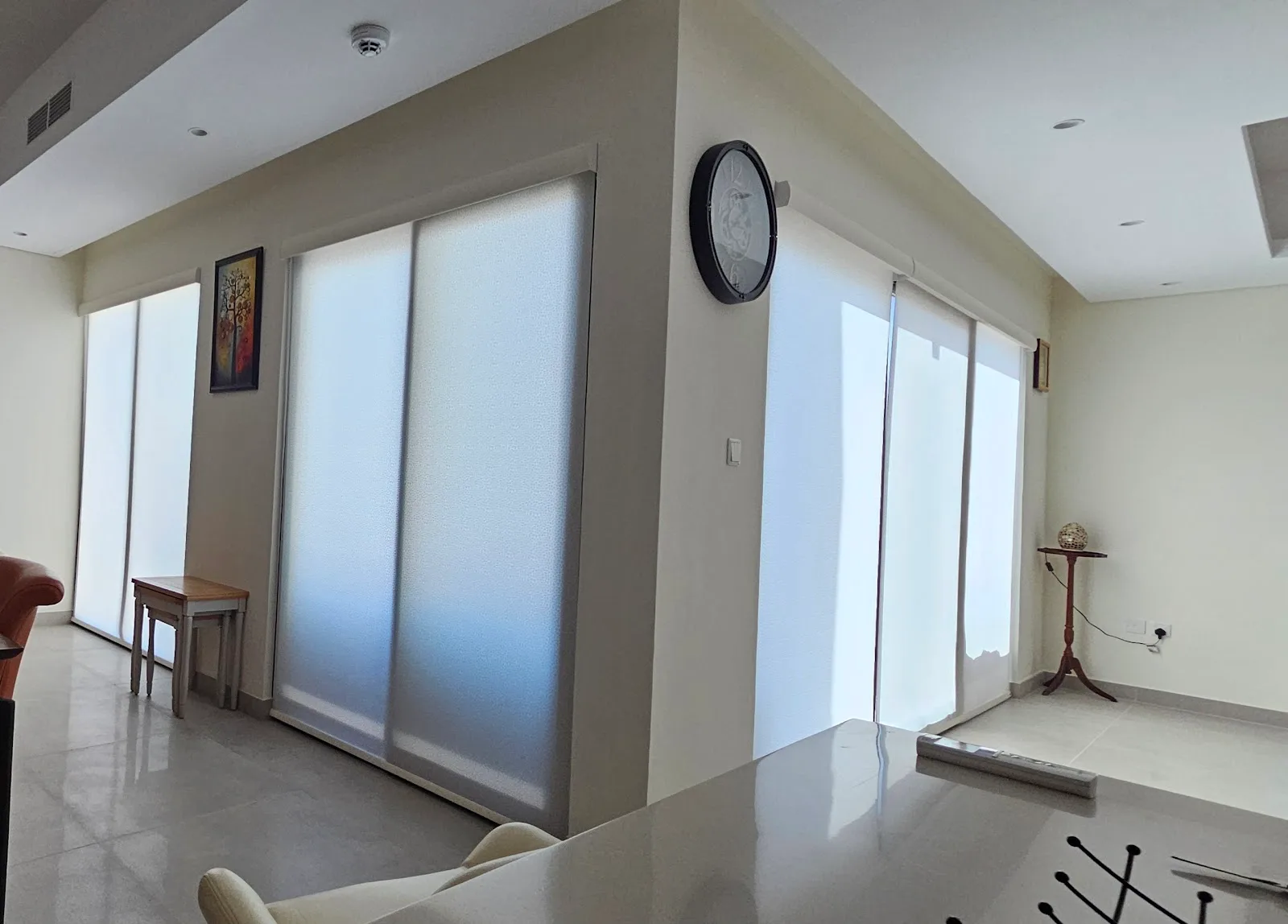 Room corner with light-filtering roller blinds on sliding doors