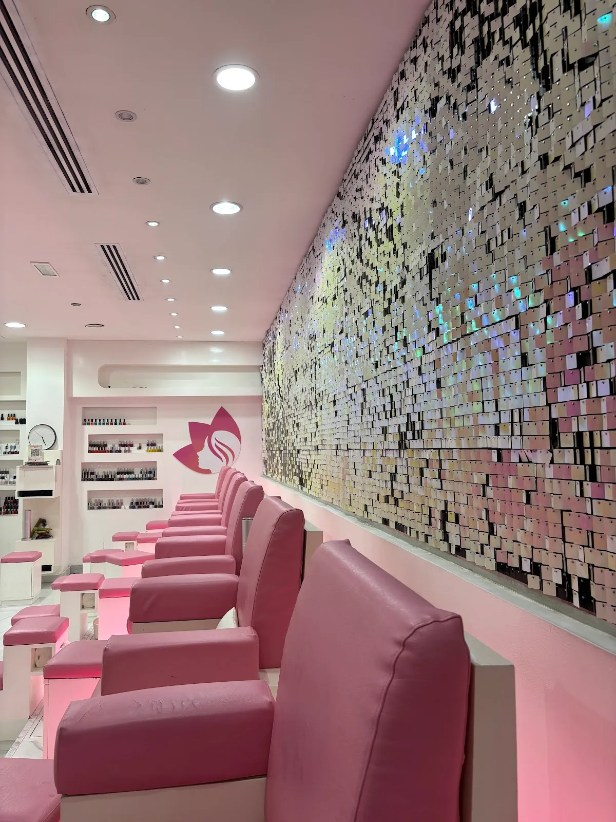 Pink pedicure chairs beside a sparkling feature wall