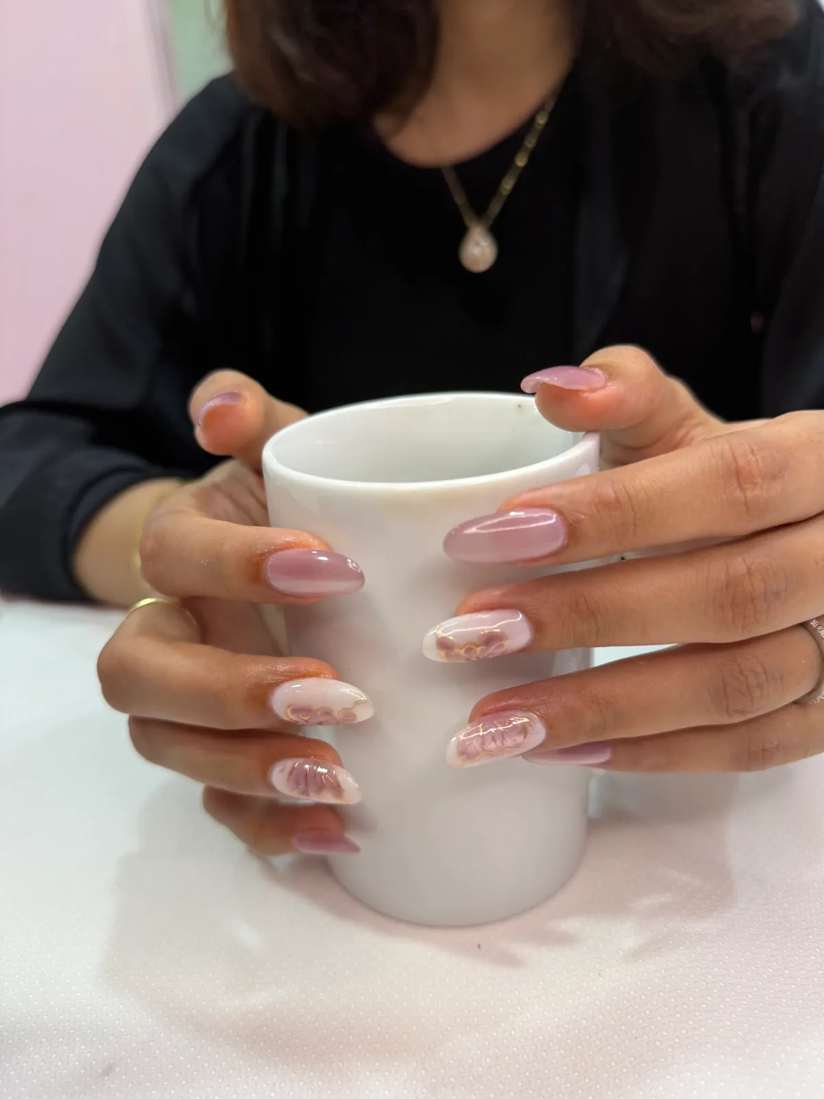 Hands with marble-effect nail art holding a mug