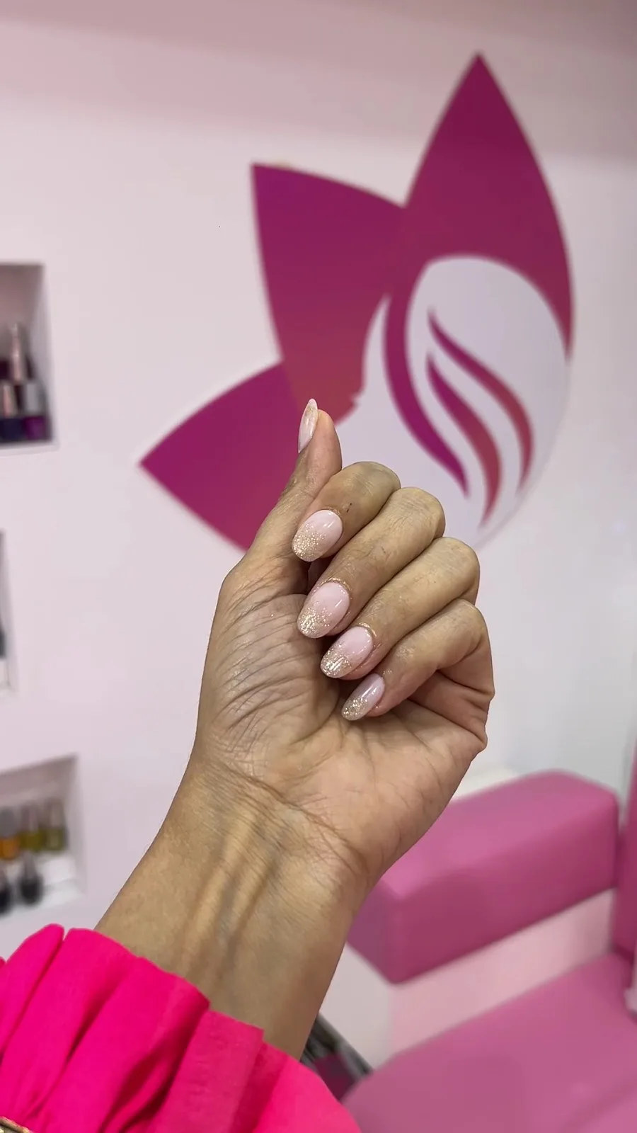 A guest's fresh manicure in front of the salon's wall mark