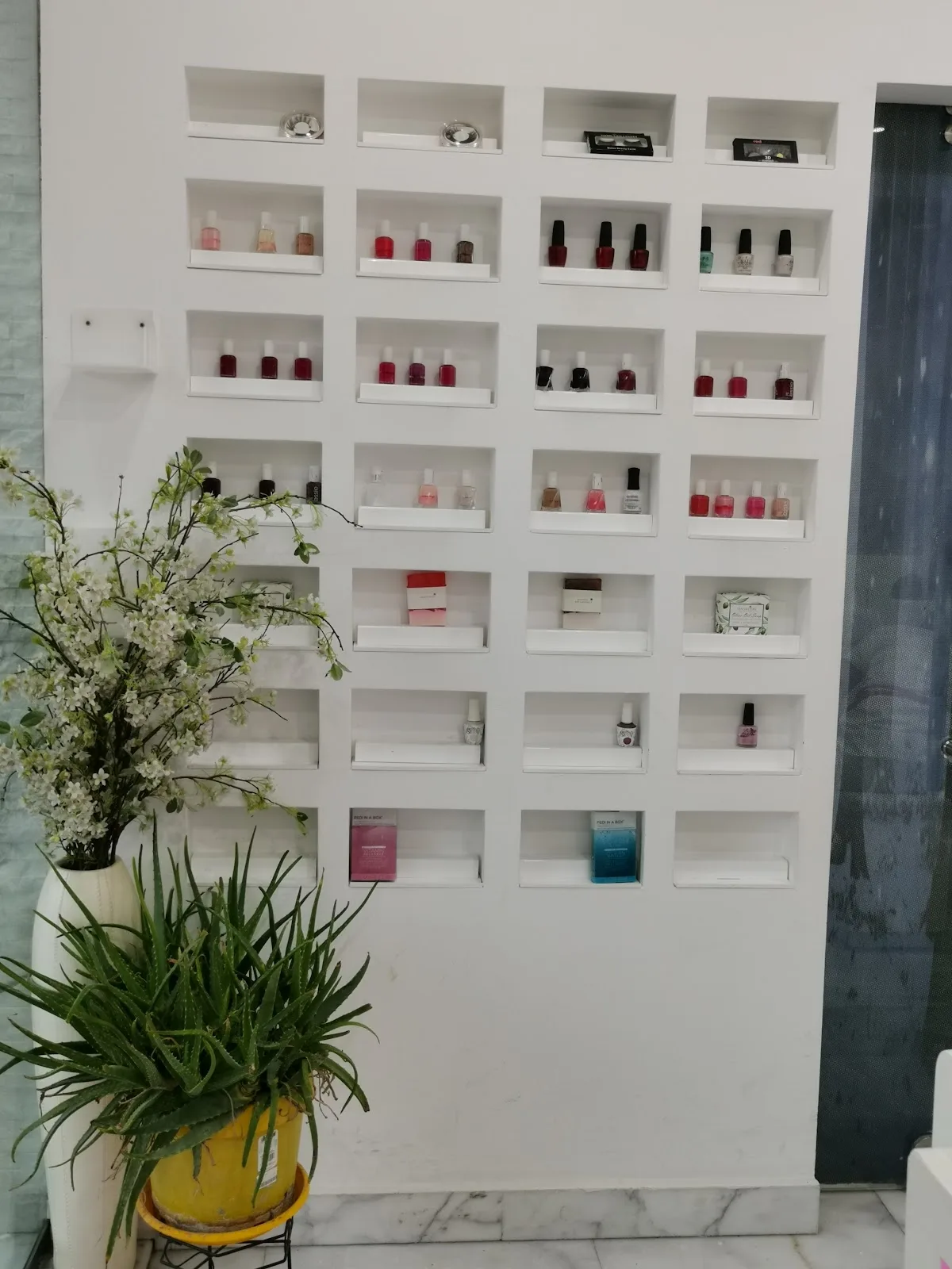 Wall display of nail polish shades beside fresh greenery