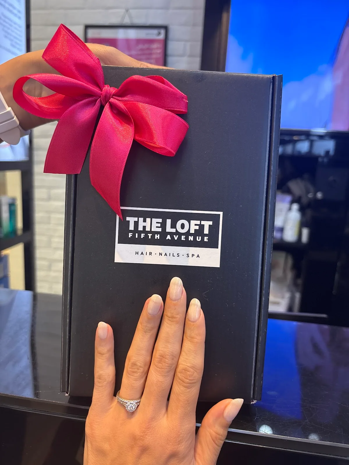 Black The Loft Fifth Avenue gift box tied with a red ribbon