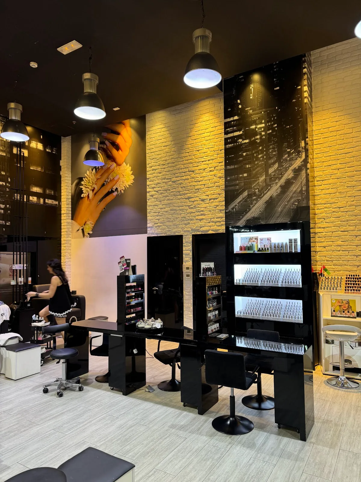 Warmly lit nail bar with black stations, brick walls and a lacquer wall