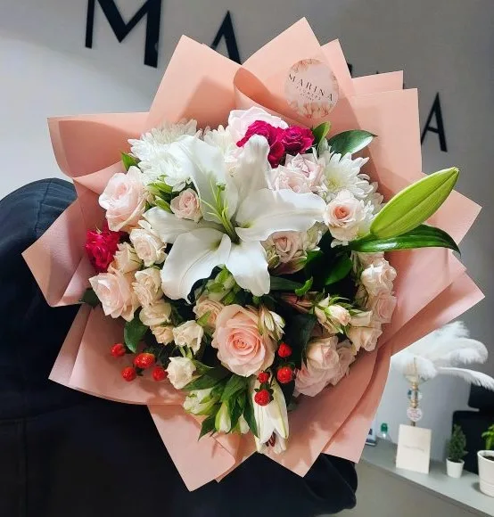 A bouquet of red roses beside a giant teddy bear in store