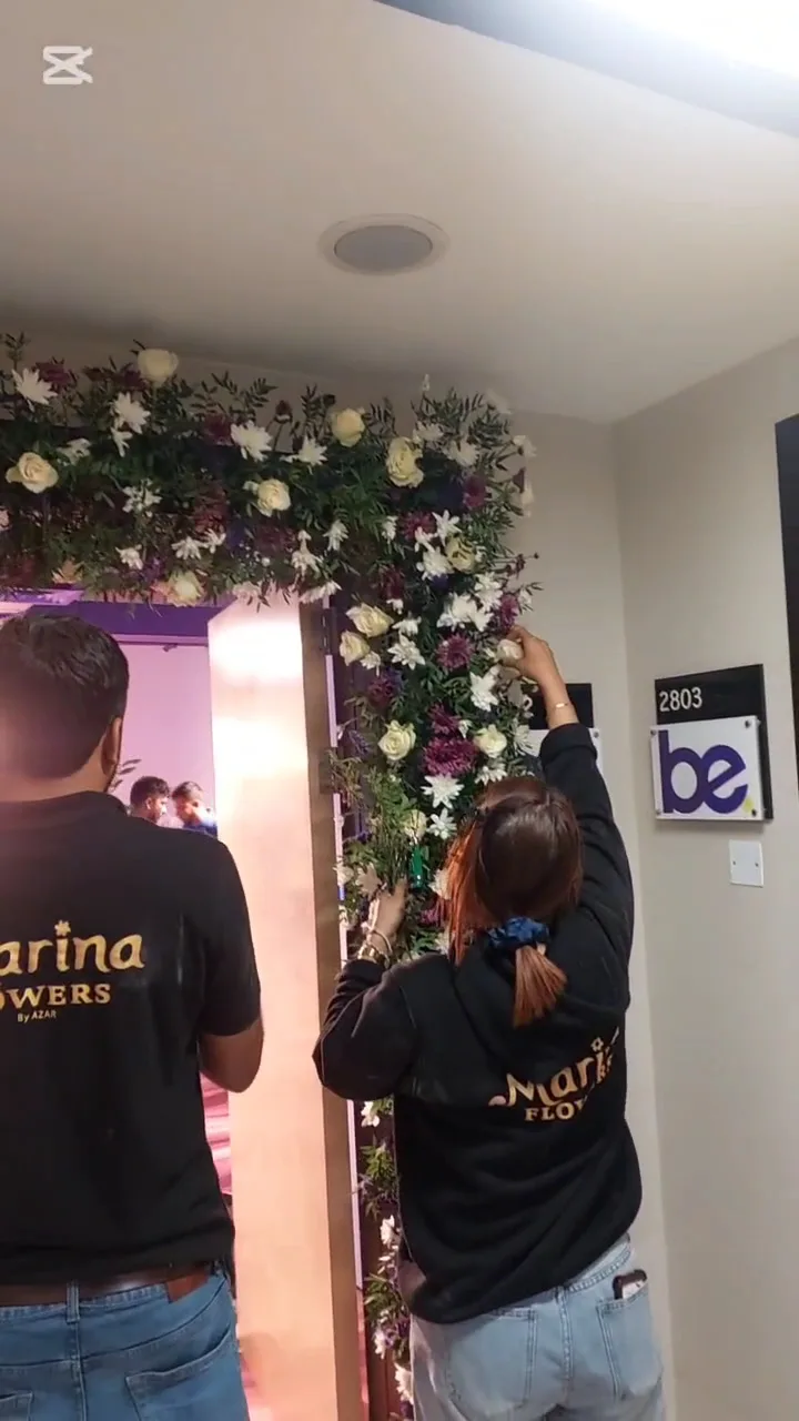 Red rose bouquets displayed beneath the Marina Flowers by Azar sign