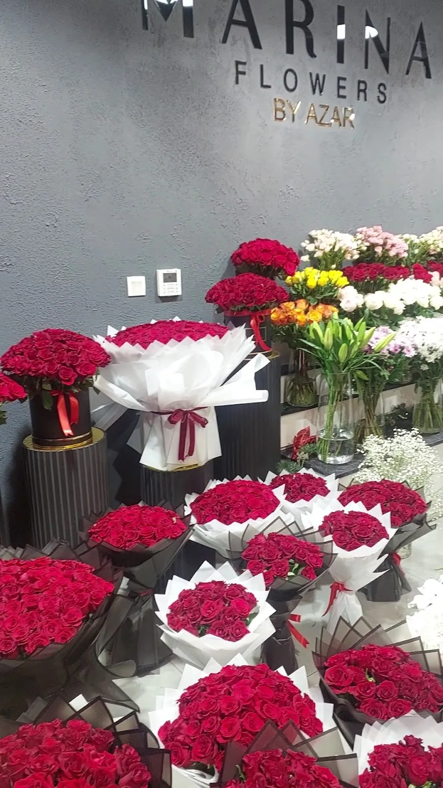 Floral event installation with red and yellow roses and a winter cabin backdrop