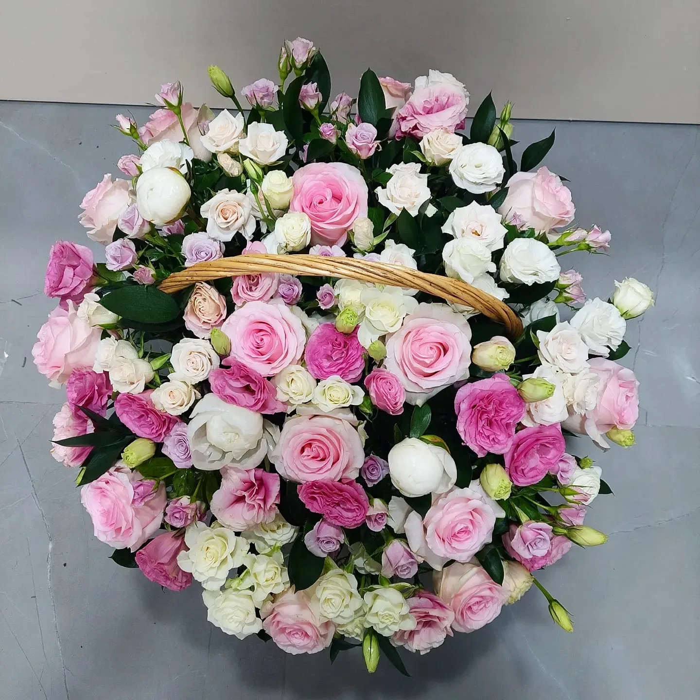 A round basket of pink and white roses, viewed from above
