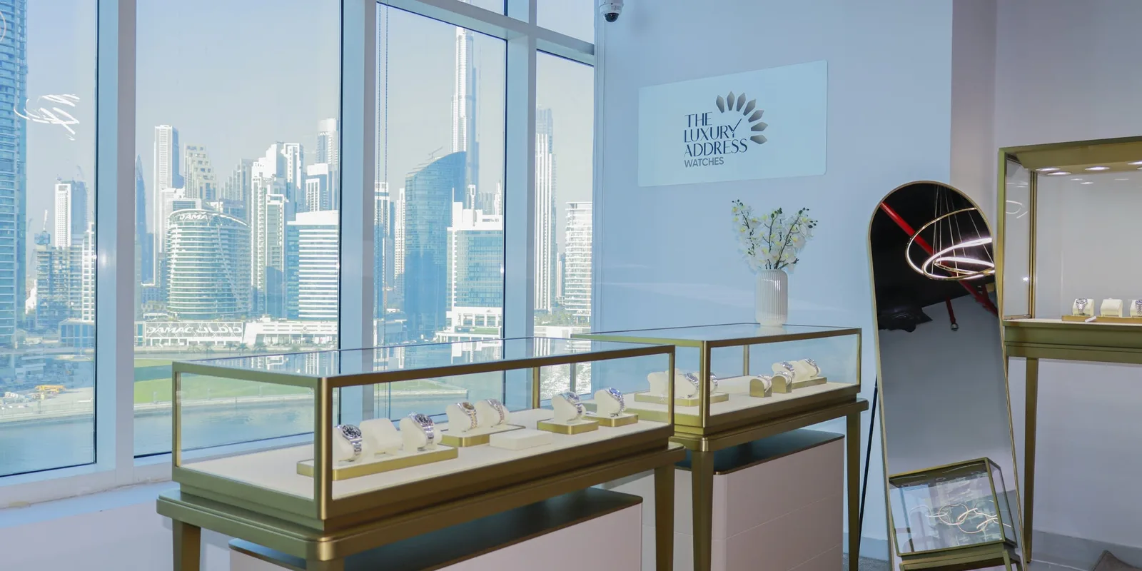 The showroom interior with gold display cases and a view of the Dubai skyline