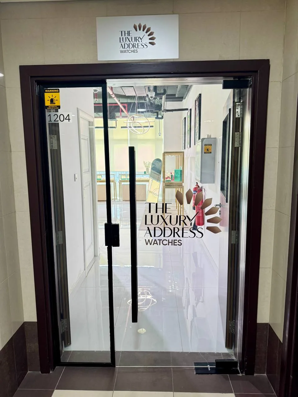 The glass entrance of suite 1204 with The Luxury Address Watches branding