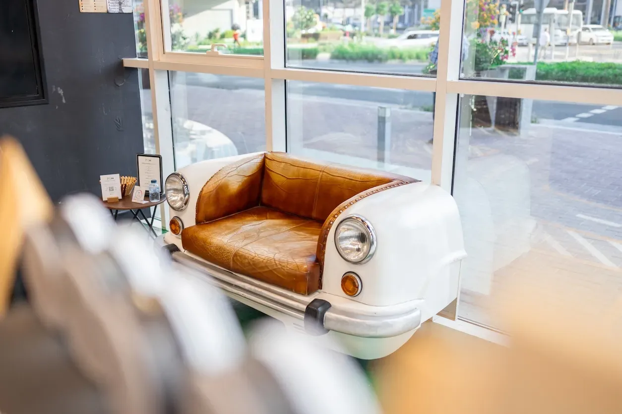 A vintage car front converted into a leather waiting sofa by the window