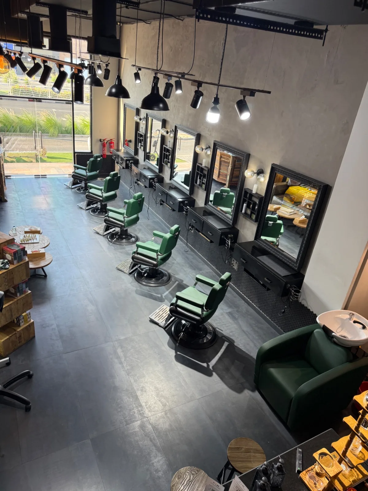 Interior of Project Hairway with a row of vintage green leather barber chairs under amber lighting