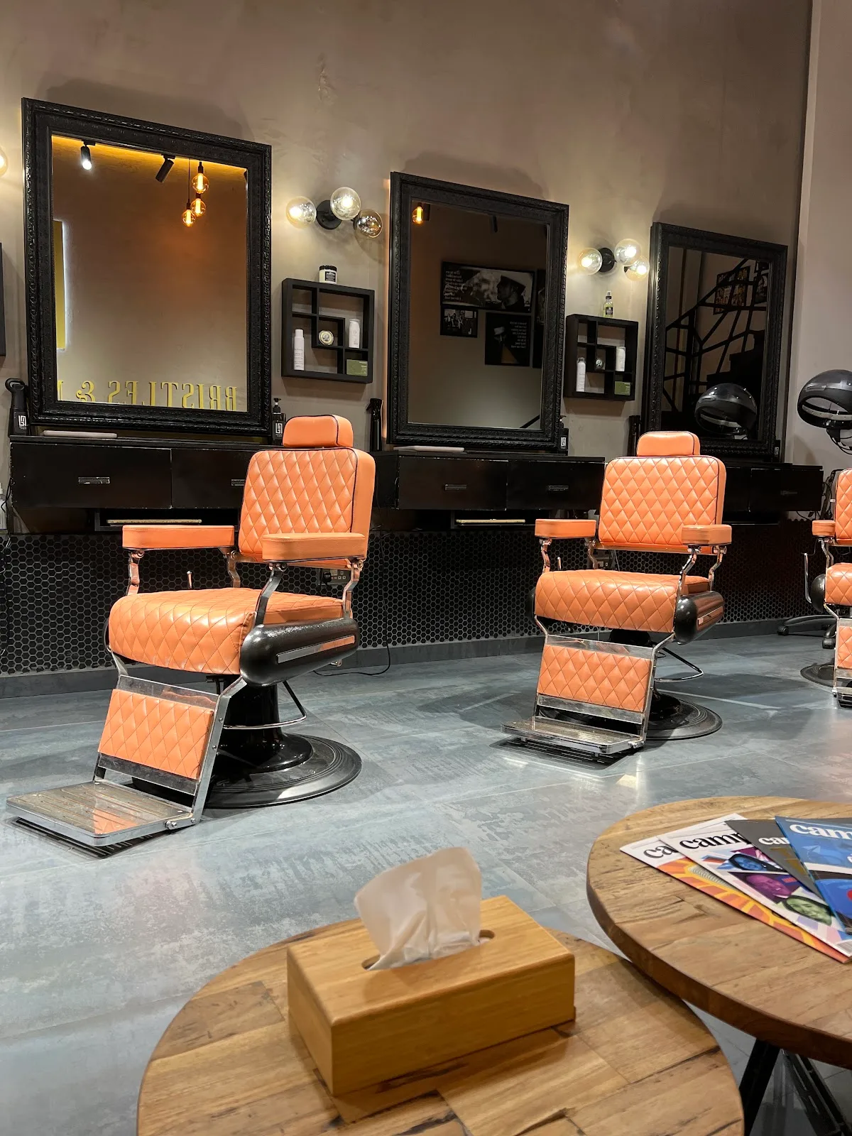 Diamond-tufted leather barber chairs in front of framed mirrors