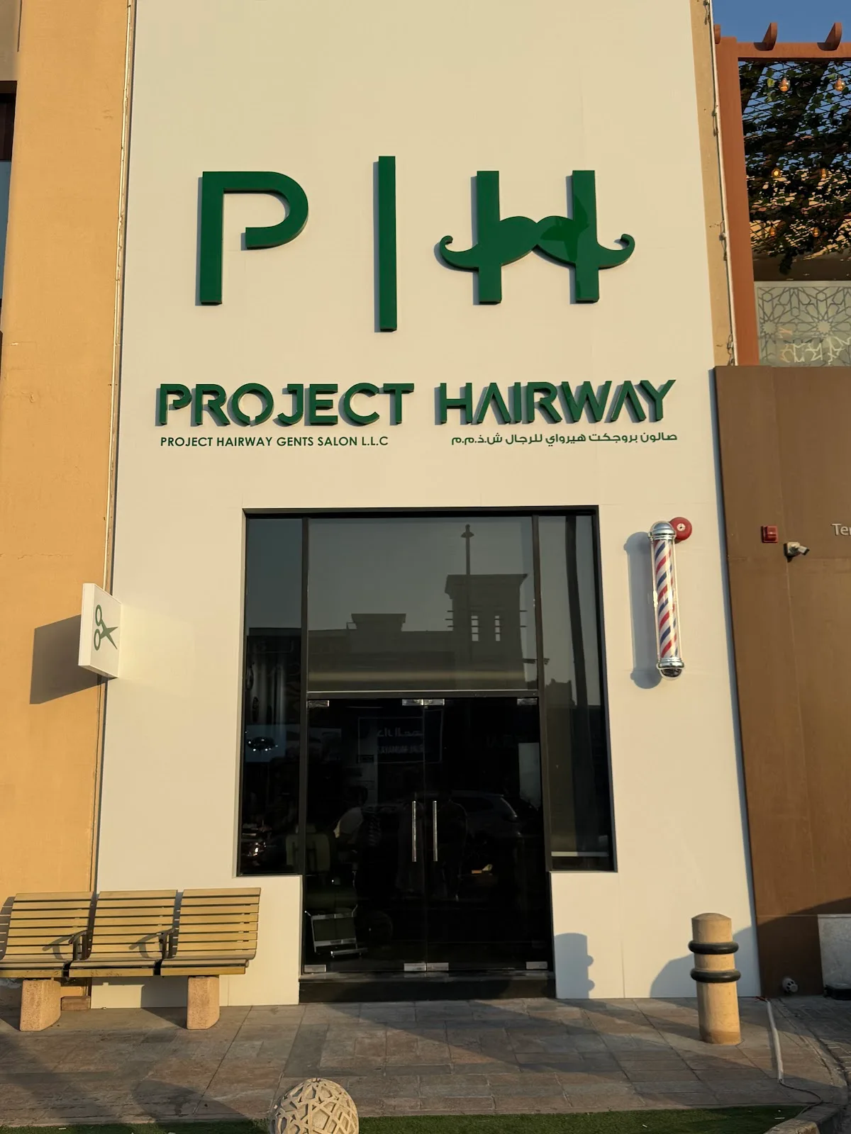 Project Hairway storefront with green signage and a barber pole in daylight