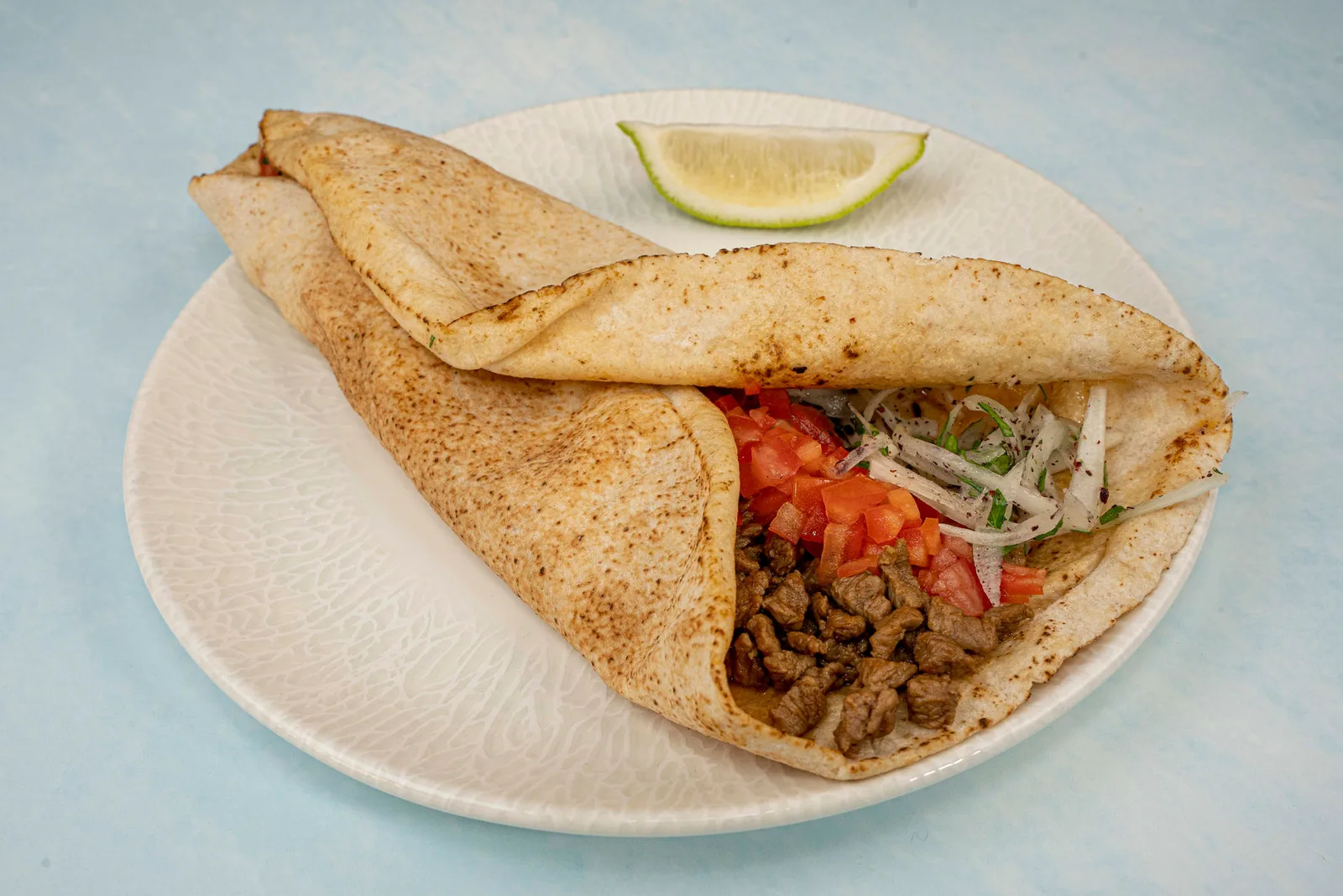 Beef dürüm wrap with tomato, onion and sumac