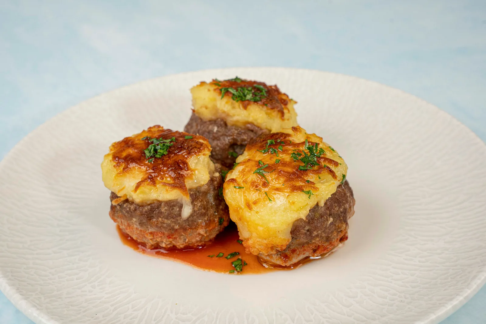 Oven-baked köfte topped with cheesy potato