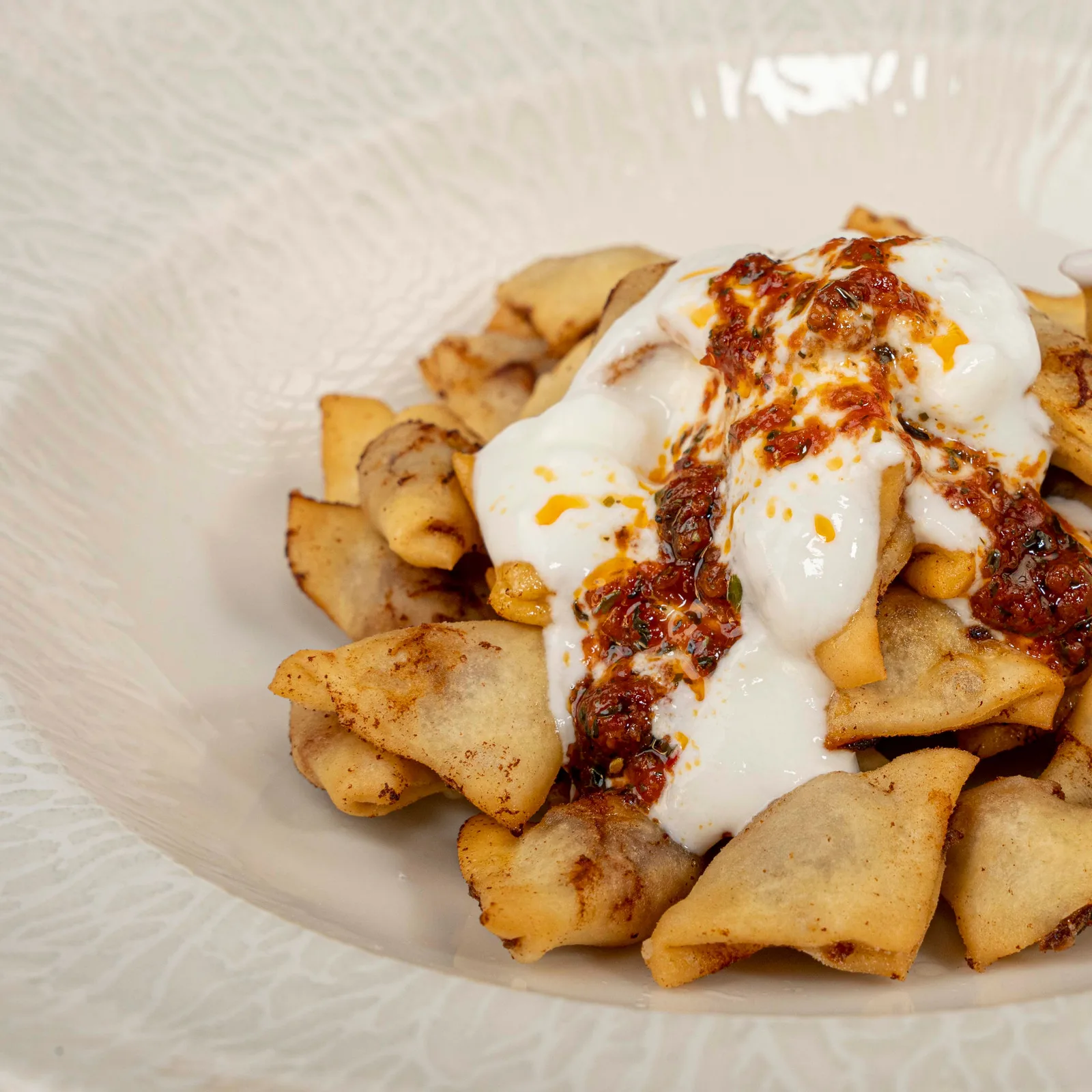 Fried mantı topped with garlic yoghurt and chilli butter