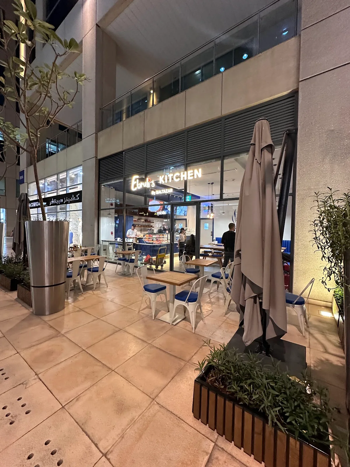 Ebruli's Kitchen storefront lit up at night with outdoor tables