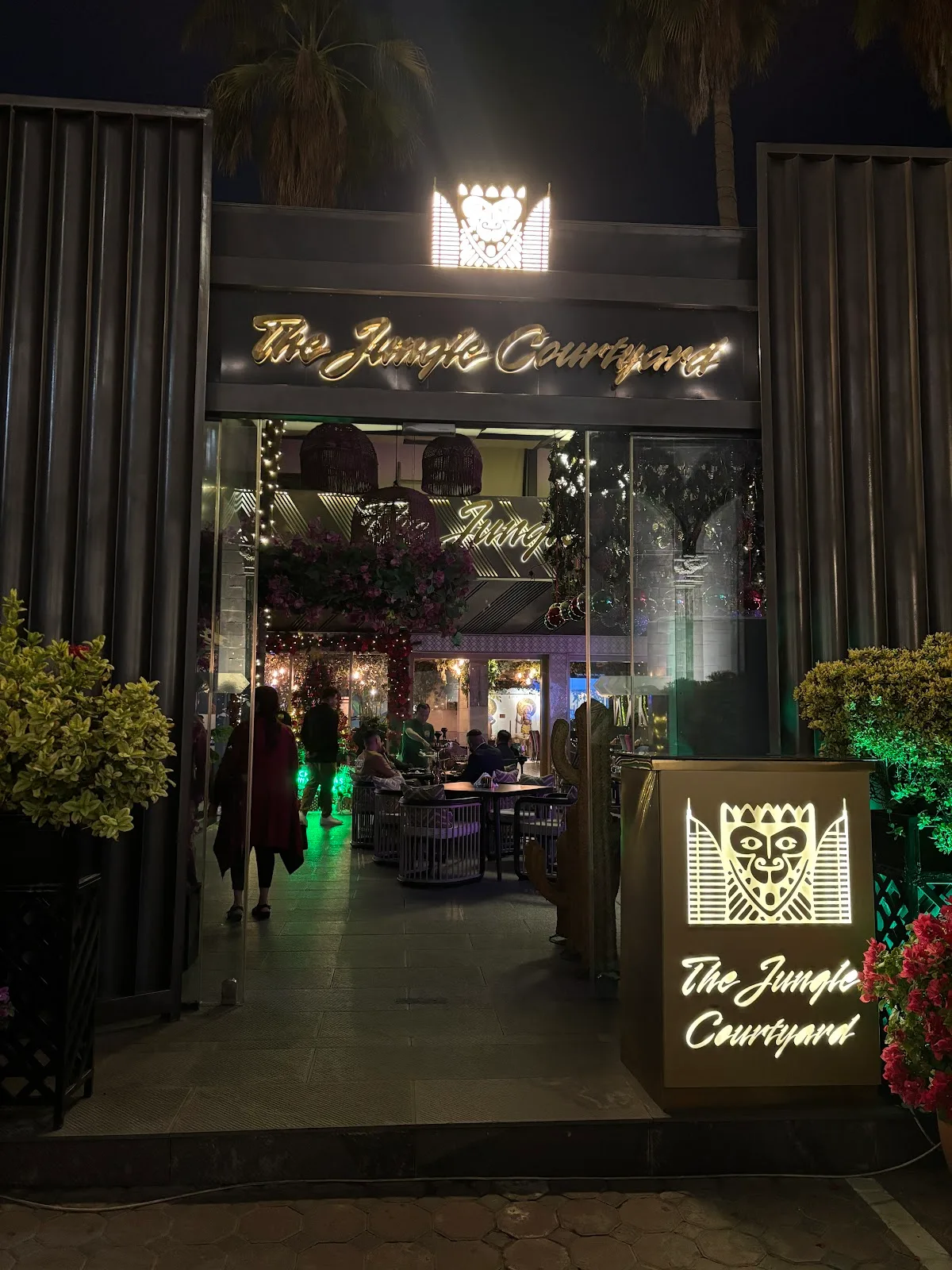 The illuminated night entrance of The Jungle Courtyard with its glowing emblem and signage