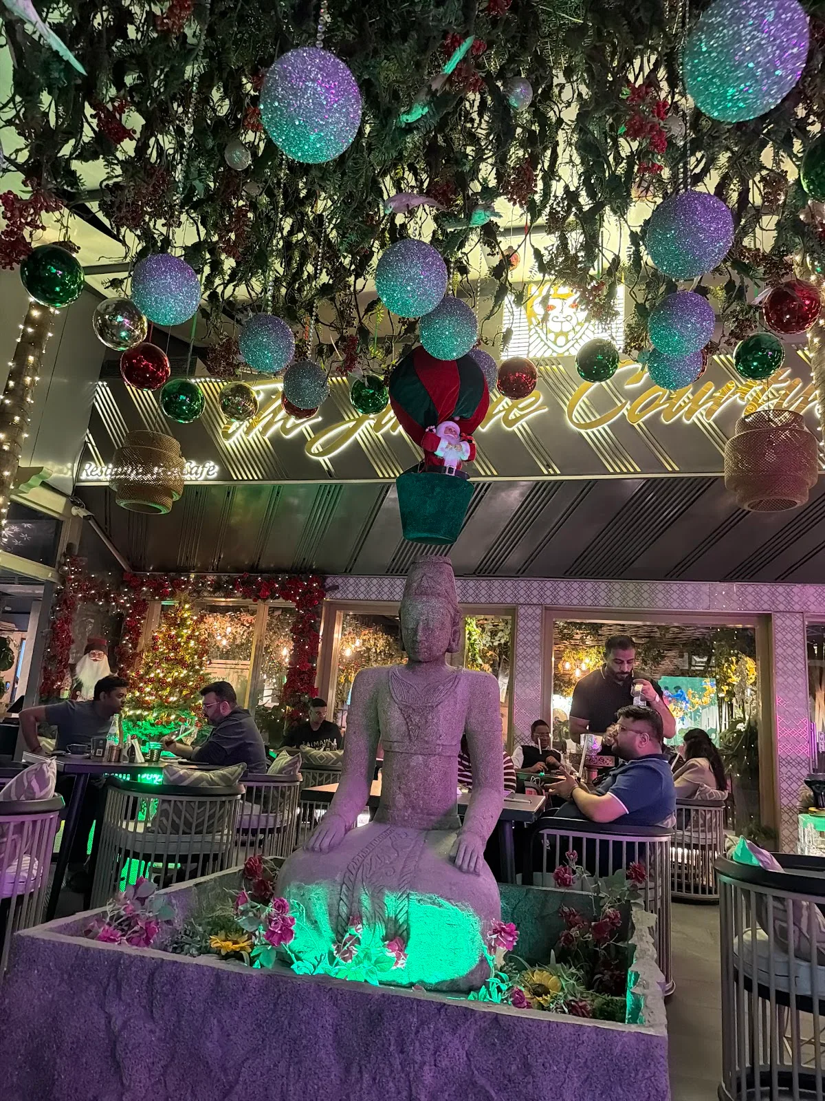 The interior decorated for the festive season with hanging baubles above a stone seated statue and diners