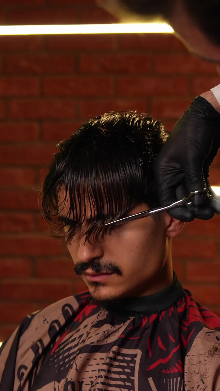 Scissor cut in progress against a brick wall