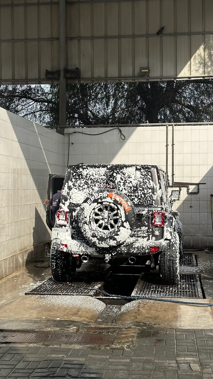 An SUV covered in white snow-foam inside a Zenith wash bay