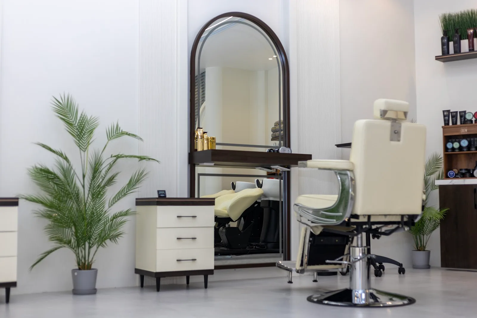 Cream styling chair beside an arched mirror and potted palm