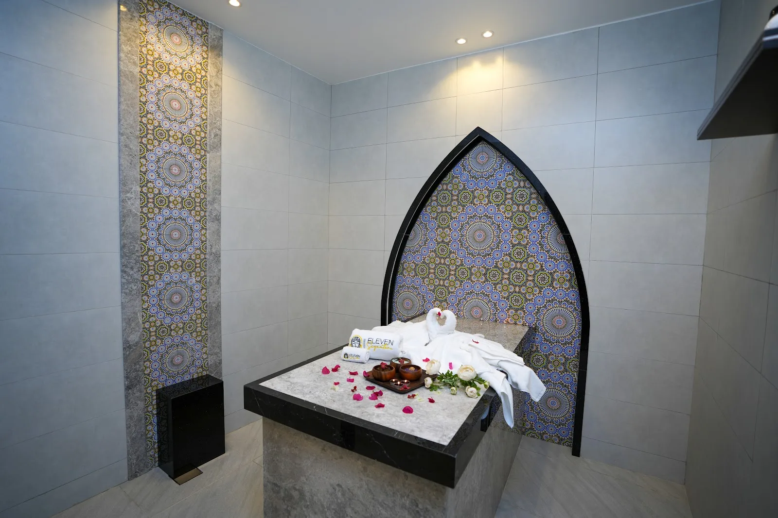 Moroccan hammam suite with patterned mosaic tile and a carved stone bench