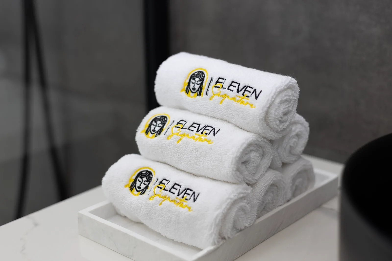 Folded white towels embroidered with the Eleven Signature mark