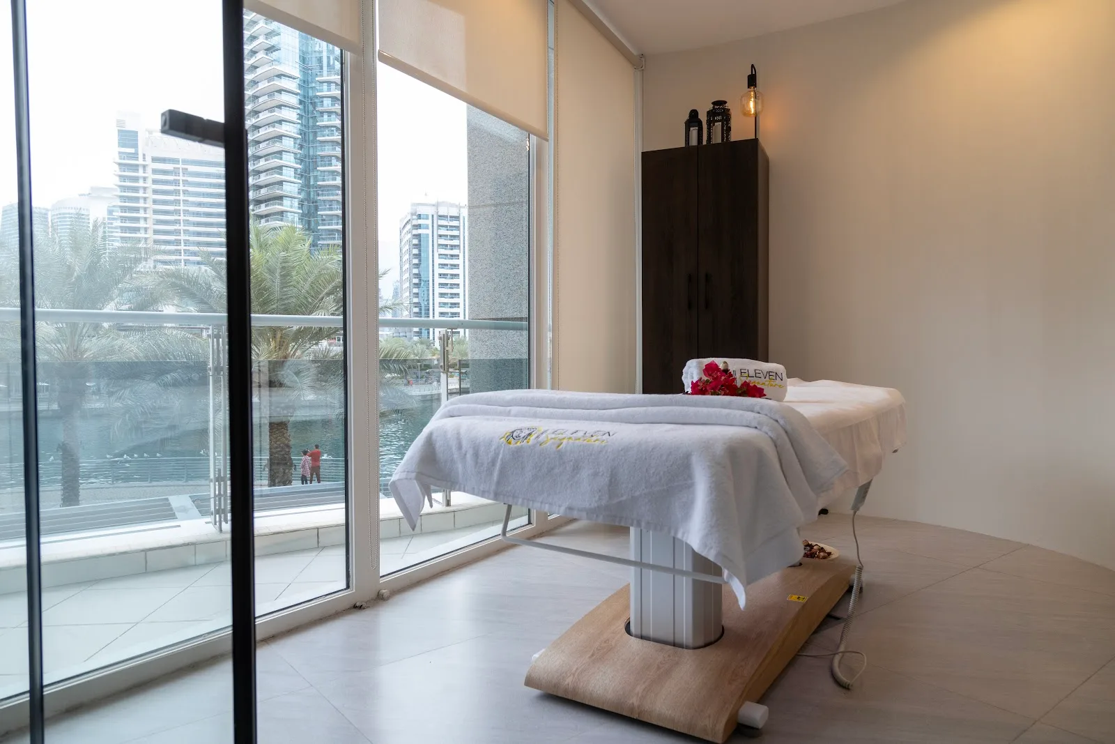 Treatment bed beside a floor-to-ceiling window with Dubai Marina views