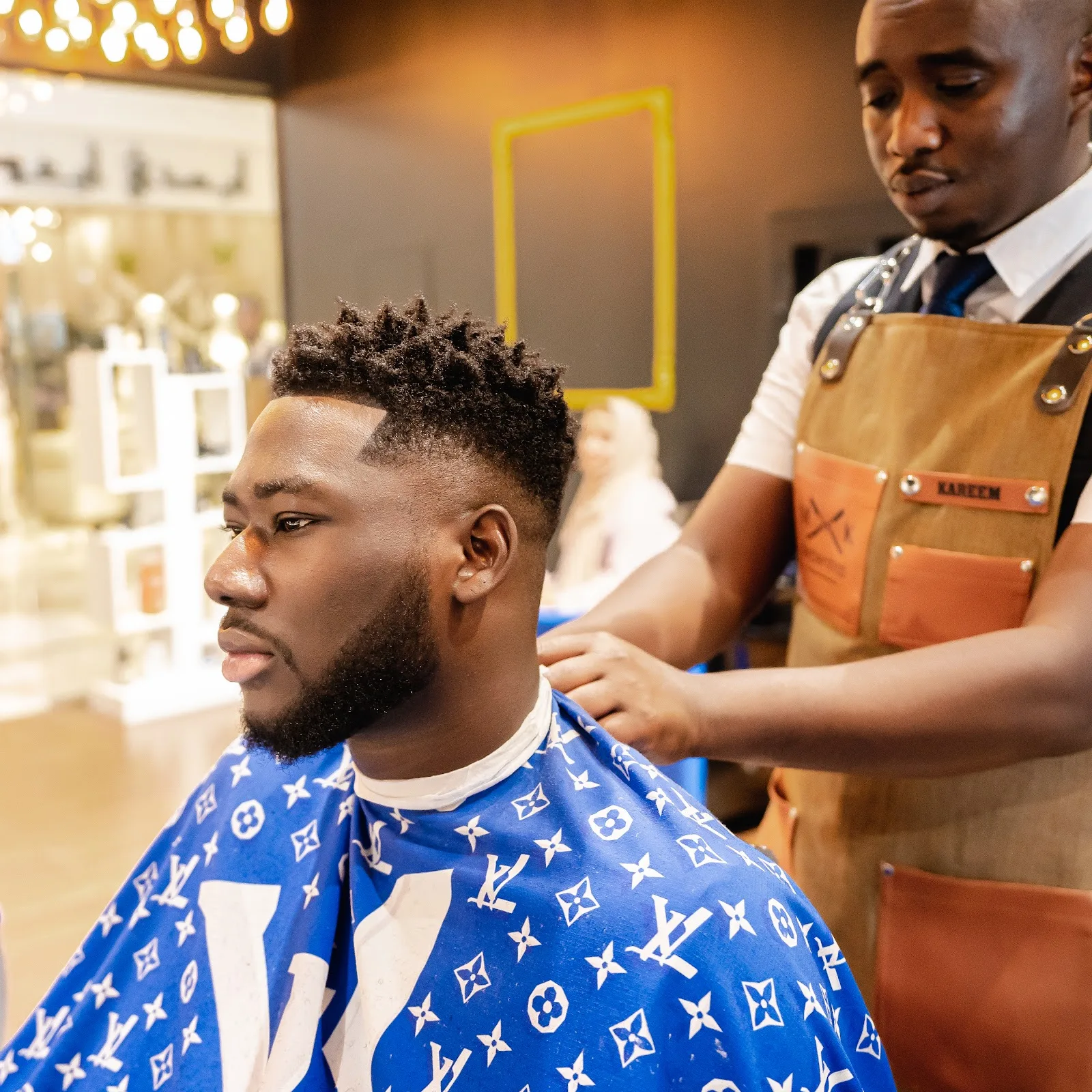 A barber finishing a sharp fade on a client at MK Barbershop
