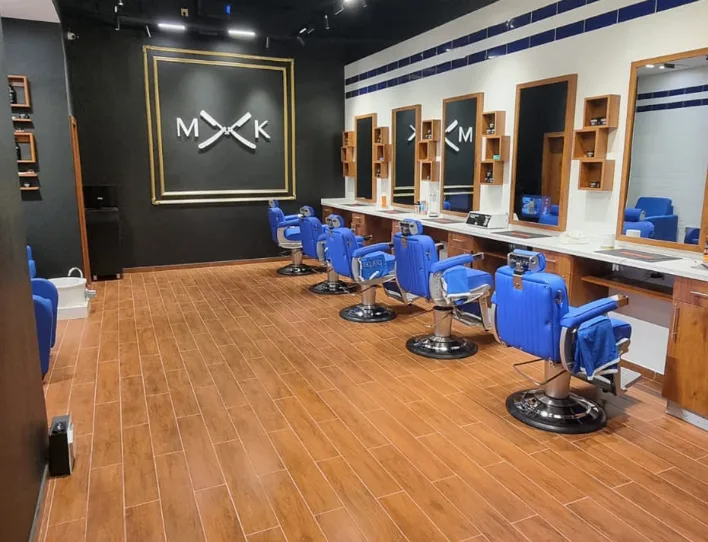 MK Barbershop interior with the gold-framed MK crossed-razor mark on a dark wall