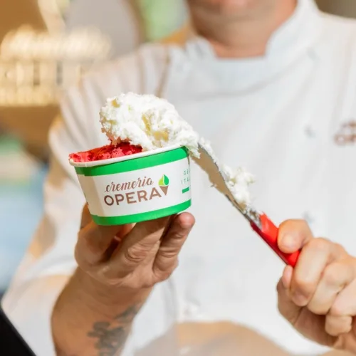 A chef finishing a cup of gelato with cream