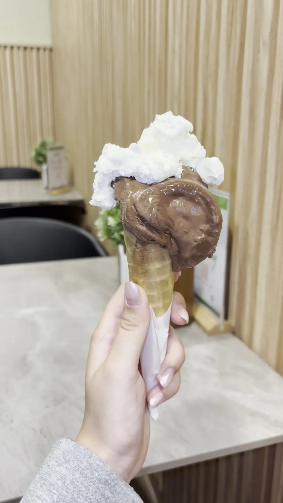 A chocolate gelato cone topped with whipped cream