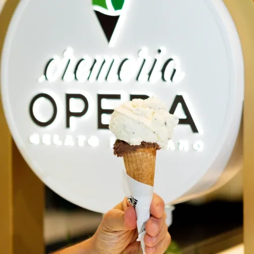 A cone held in front of the Cremeria Opera sign