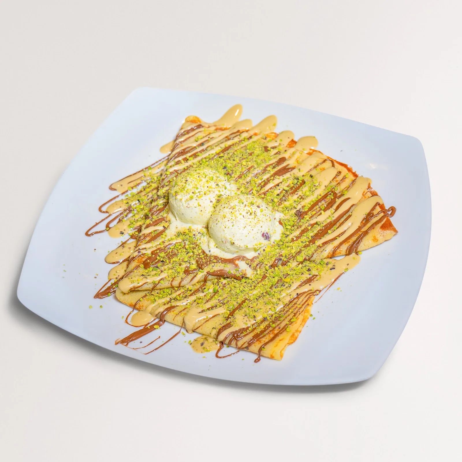 A crêpe with vanilla gelato scoops and crushed pistachio