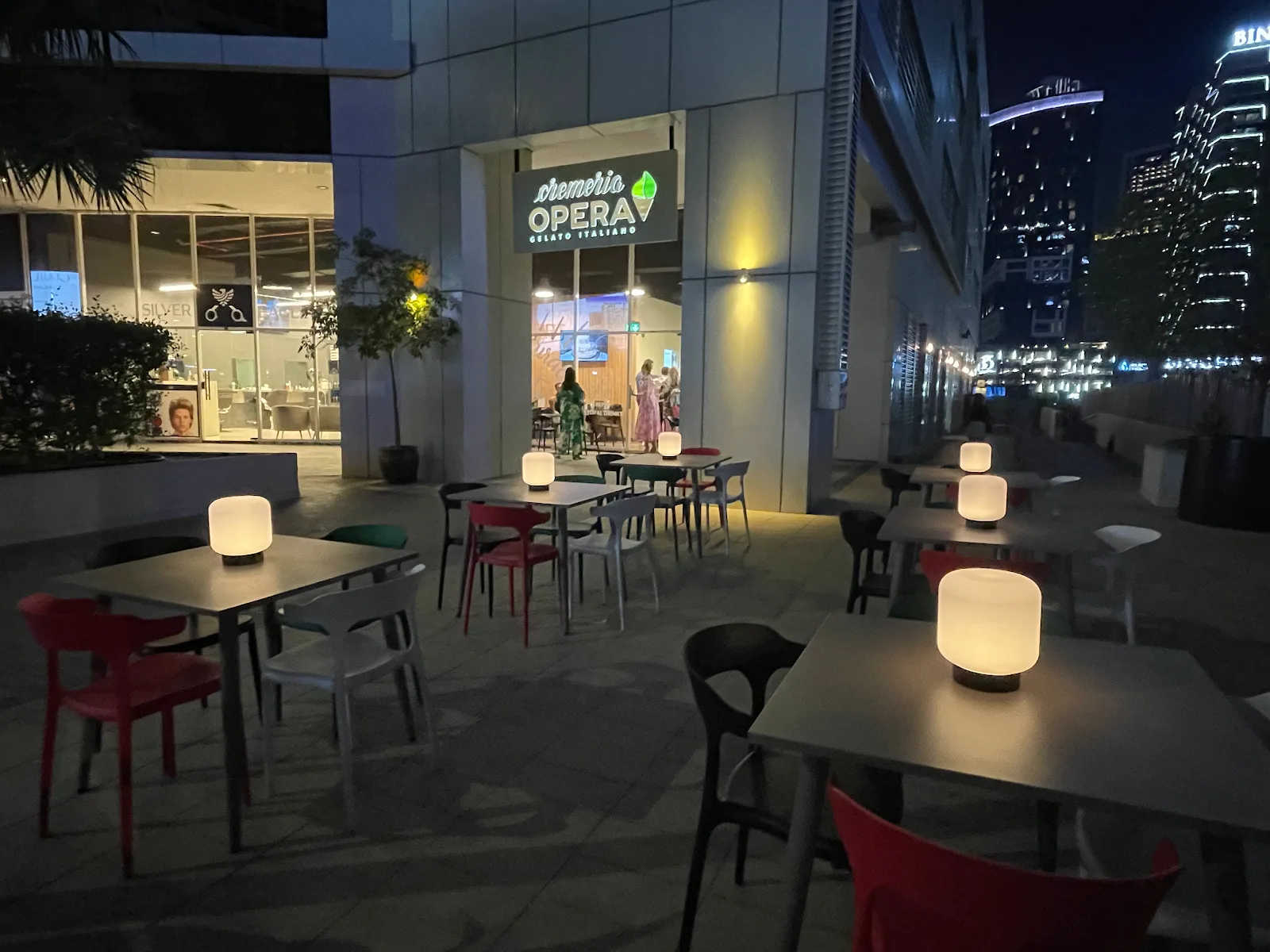 Outdoor terrace seating at Cremeria Opera at night on the Business Bay canal