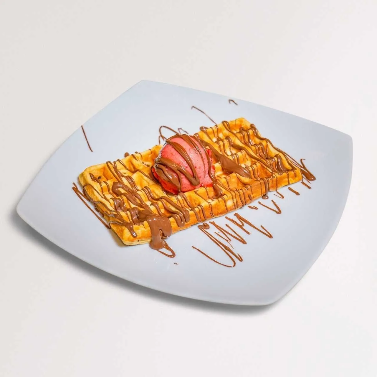 A Belgian waffle topped with a scoop of gelato and chocolate drizzle