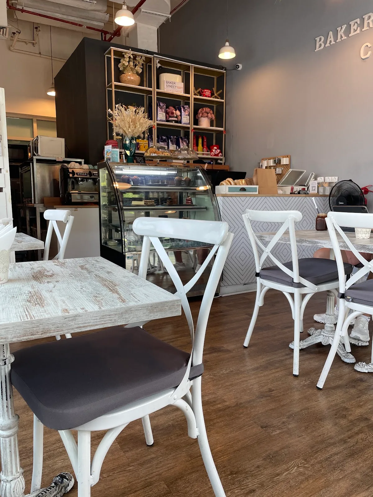 Café interior with white bistro chairs and a pastry display case