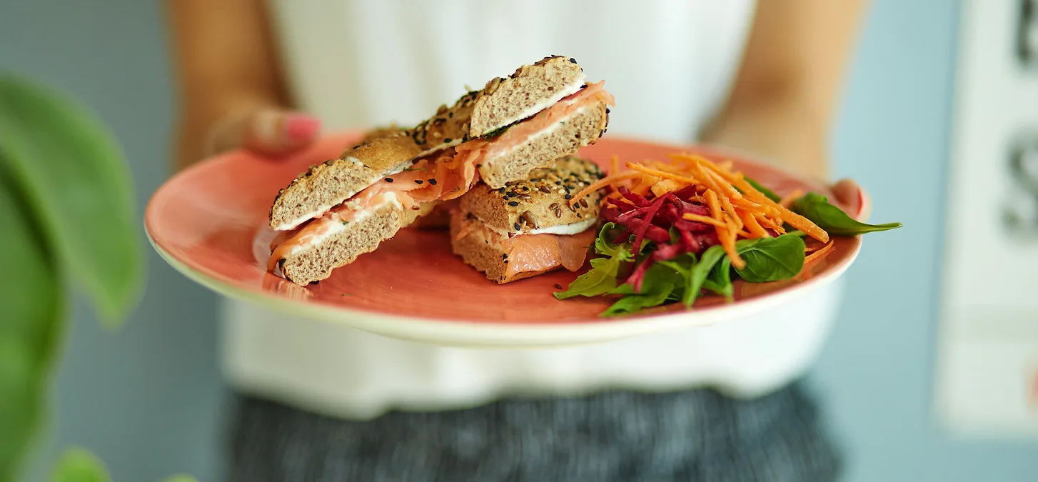 Seeded bagel with salmon and cream cheese, served with a side salad