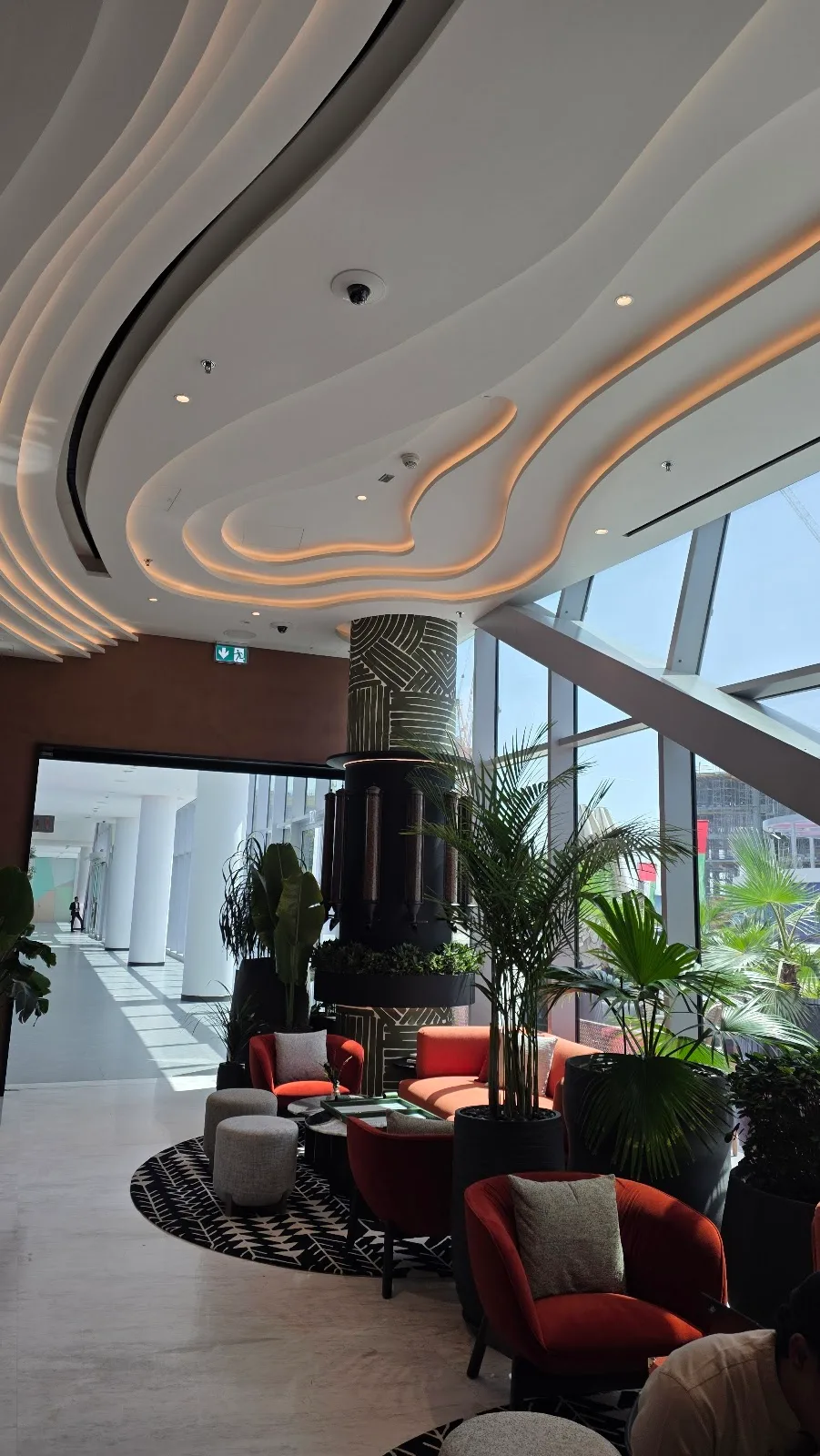 Sculptural lit ceiling above terracotta lounge chairs