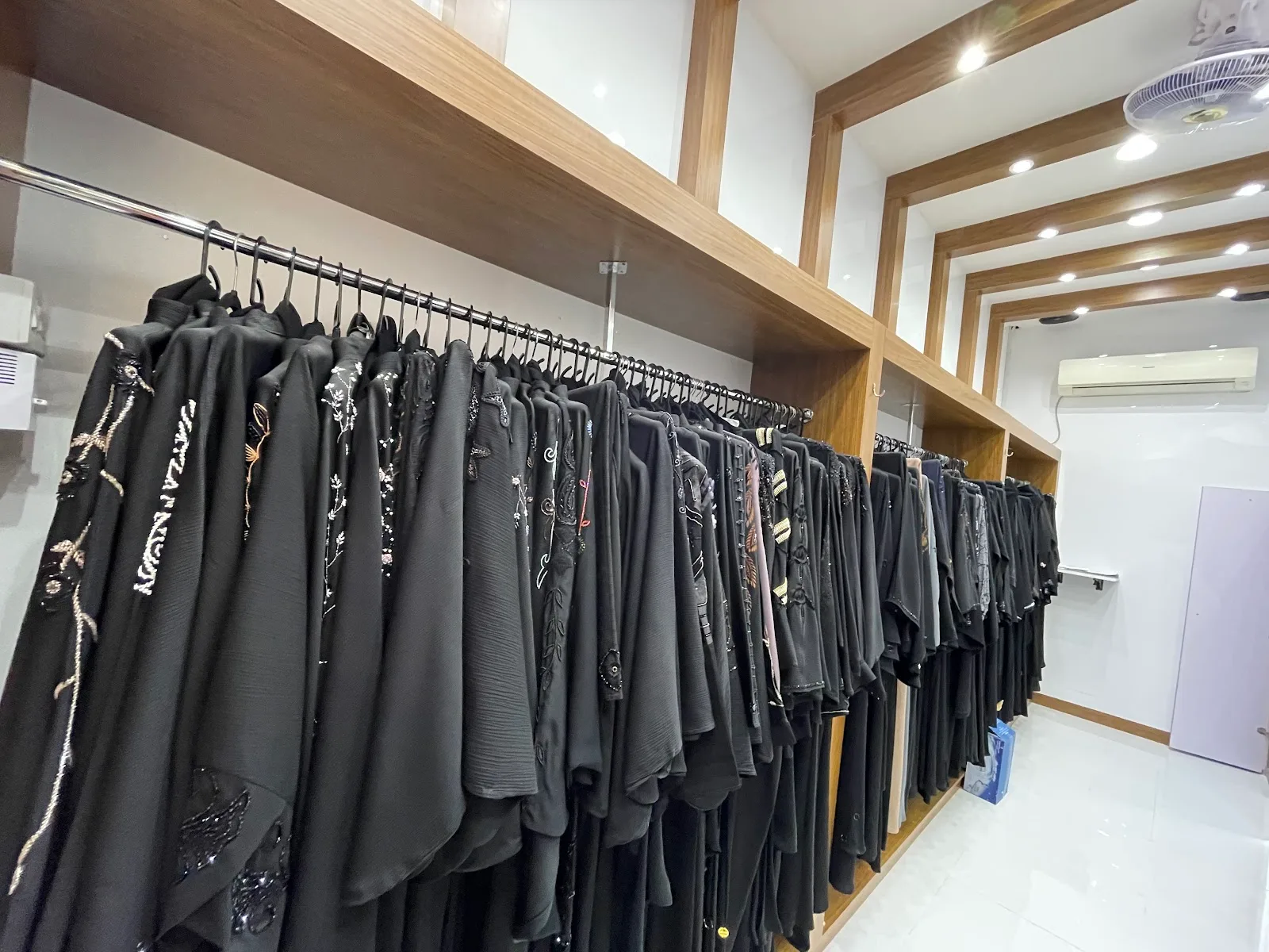 Long rail of black abayas under warm shop lighting