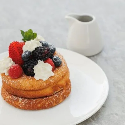A stack of pancakes topped with berries and cream