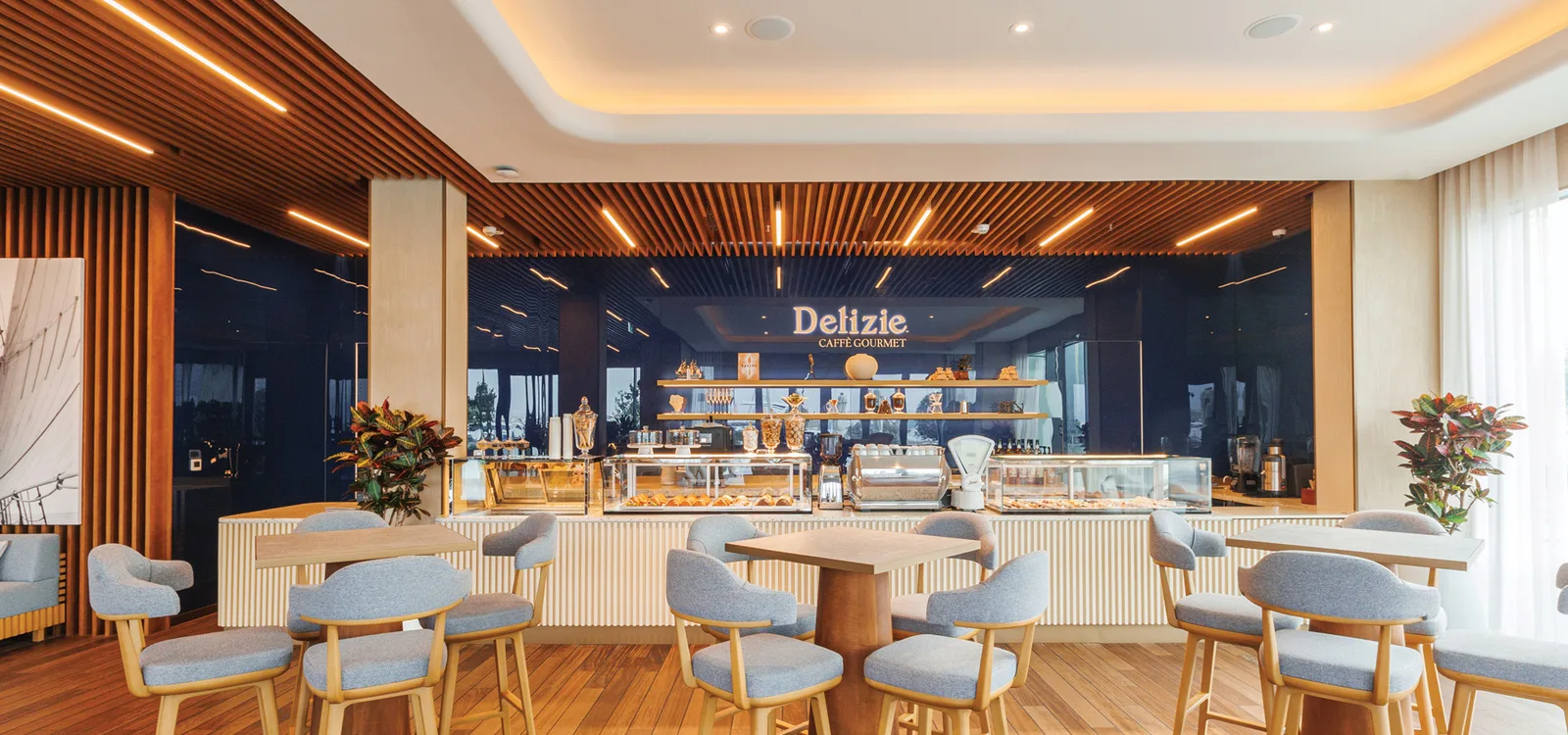 Interior of Delizie Caffè Gourmet — bakery counter beneath the illuminated brand sign at Dubai Harbour