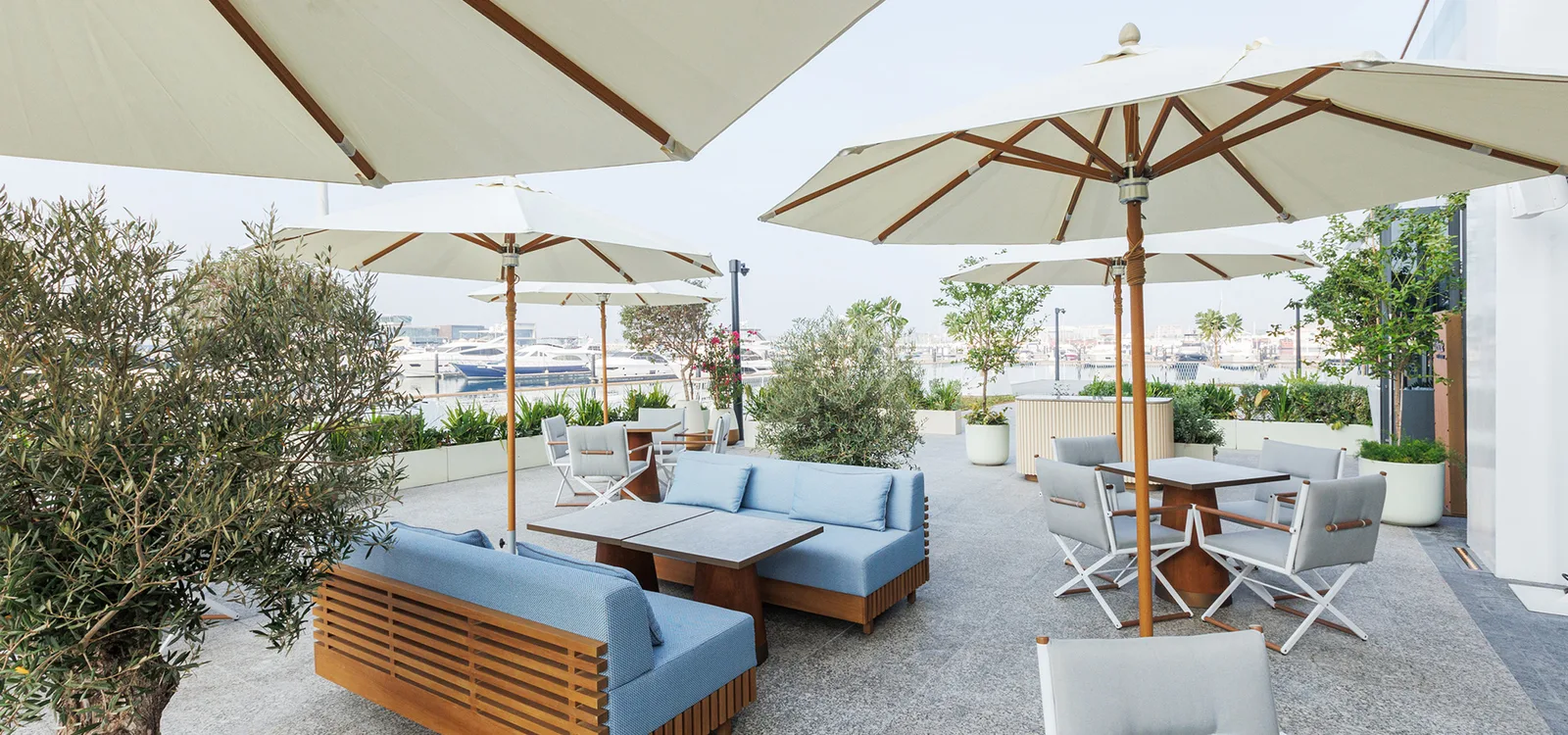 Shaded marina terrace with umbrellas overlooking yachts