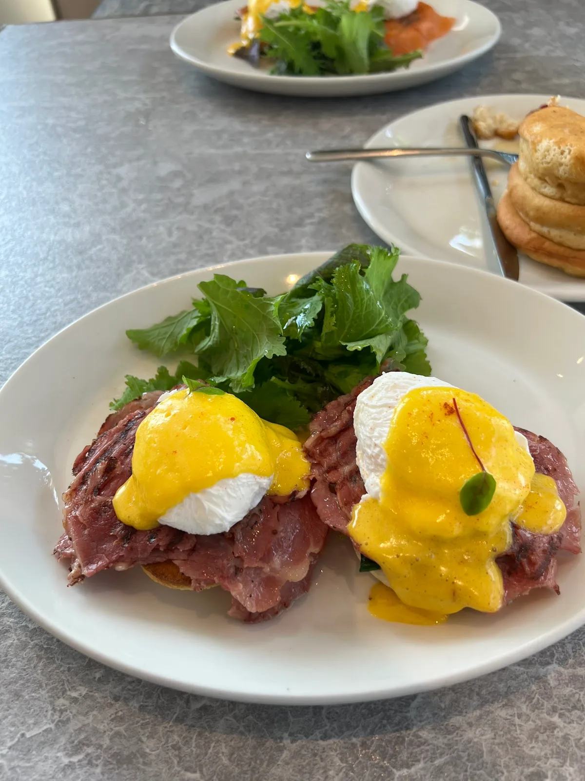 Eggs benedict with pastrami and a side salad
