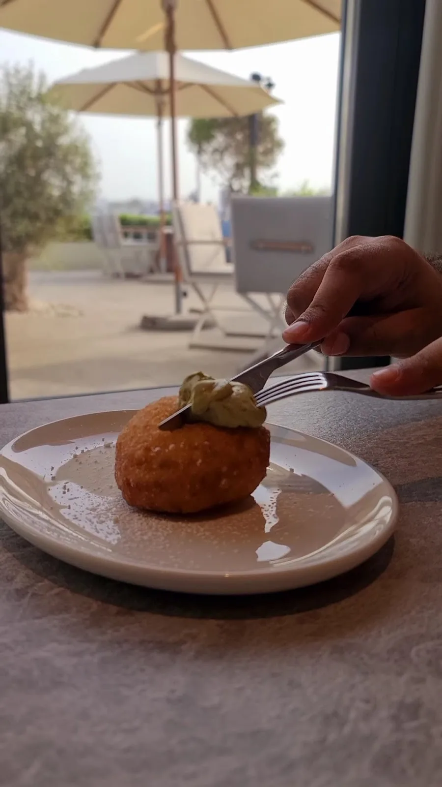 A golden Italian rice ball with pistachio cream