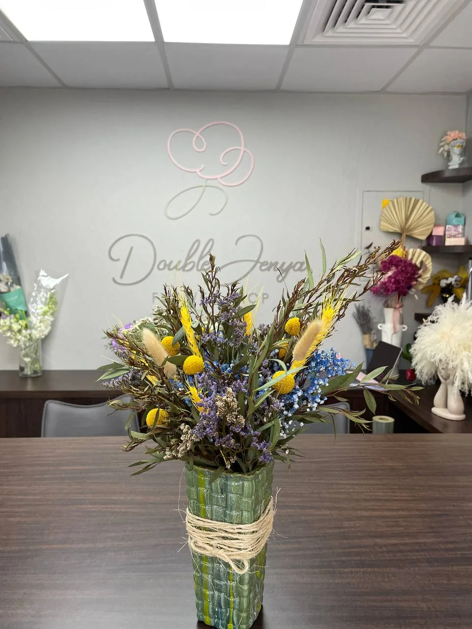 Dried-flower arrangement with billy buttons and lavender in a woven green vase